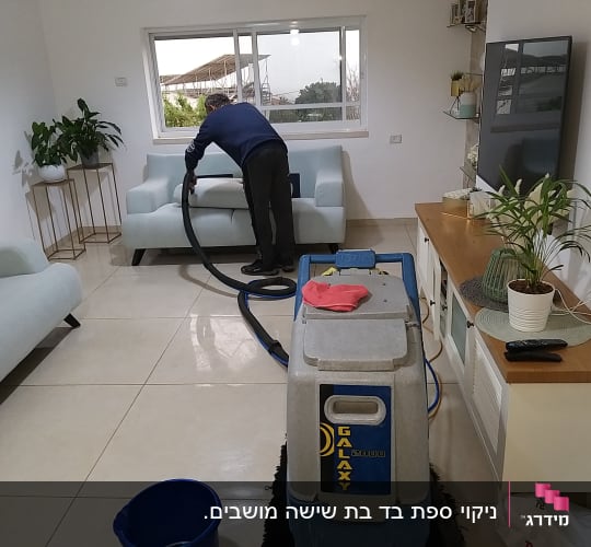 אדם מנקה ספה עם מכונת ניקוי ושואב אבק